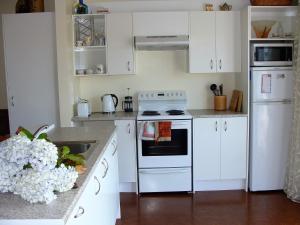 奥玛鲁奥马璐粉红色度假屋的厨房配有白色橱柜和白色炉灶烤箱。