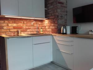 华沙Studio Nowy Świat的厨房配有白色橱柜和砖墙