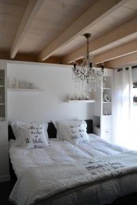 斯霍尔Vakantiehuis Olivia的卧室配有一张带吊灯的大型白色床。