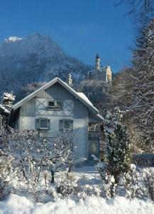 旧天鹅堡始于1901年的阿尔布雷希特住宿加早餐旅馆的雪中的房子,背景是山