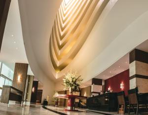 库里提巴Hotel Dunamys Curitiba的大堂设有大型天花板和桌椅。