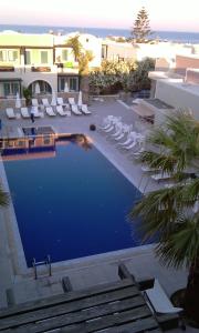 卡马利玫瑰湾酒店的一座带白色躺椅的游泳池,位于大楼旁
