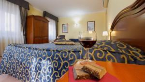 波扎洛阿达维拉酒店的坐在床边的桌子上喝一杯葡萄酒