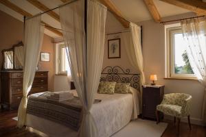 Agugliano兰迪格格拉那罗酒店的一间卧室配有一张天蓬床和一把椅子