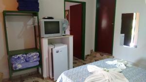 圣托梅-达斯莱特拉斯Pousada Recanto do Sossego的客房设有1张床、1台电视和1个电视架。