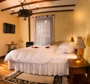 里奥班巴安达卢西亚旅馆的卧室配有白色的床铺,上面有红色的鲜花
