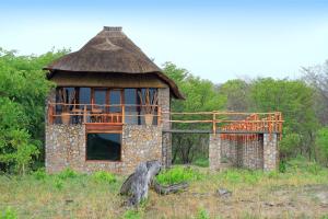 DeteGwango Elephant Lodge的一座古老的石头建筑,在田野上拥有茅草屋顶