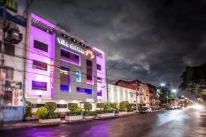 墨西哥城Hotel Villa del Mar的夜幕降临的城市街道上的紫色建筑