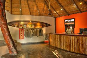马翁Thamalakane River Lodge的站在一间有橙色墙壁的酒吧里的女人