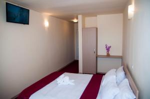 布拉索夫Dumbrava Minunata的一间卧室配有一张带白色床单的床和墙上的电视。