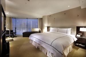 台北柯达大饭店 台北敦南的卧室配有一张白色大床和一张书桌