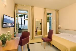 加尔多内-里维耶拉Hotel Monte Baldo e Villa Acquarone的酒店客房带一张床、一张桌子和椅子