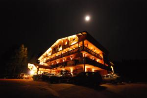 克松吕-隆日梅领小屋酒店的一座有汽车在晚上停在停车场的建筑
