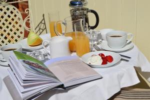 格兰瑟姆The Coach House Denton的桌上的开放式书,包括咖啡和一盘水果