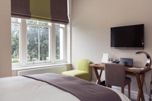 伯恩茅斯格林别墅酒店的一间卧室配有一张床、一张书桌和一台电视