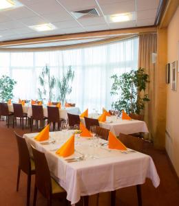 勒什Hotel Krek Superior的餐厅配有白色桌椅和橙色餐巾