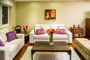危地马拉Apart-Hotel Casa Serena的客厅配有沙发和花瓶(桌子上)
