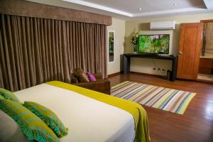 危地马拉Apart-Hotel Casa Serena的配有一张床和一台平面电视的酒店客房