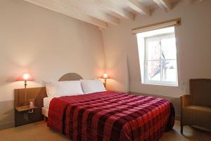 图尔地址酒店的一间卧室配有一张带红色毯子的床和窗户。
