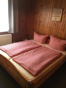 索内纳尔佩·纳斯费尔德Haus Serena oben的一张铺有红白色床单和枕头的木床