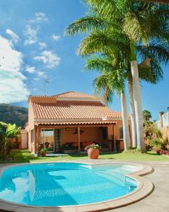 拉普拉亚蒂陶洛Villa Tauro Country Club的棕榈树屋前的游泳池