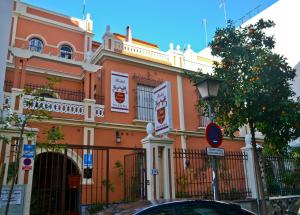 塞维利亚圣维森特2号旅馆的一座橙色的建筑,前面有栅栏