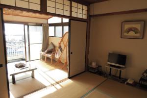 松江市福间馆日式旅馆的客厅设有滑动玻璃门和电视