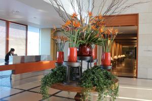 荷兹利亚First Class Marina Herzlia的大堂里摆放着红色花瓶,桌上摆放着植物