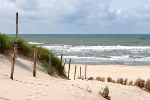 滨海卡特韦克Vakantiehuis Katwijk Andreasplein的沙滩上,有栅栏和海洋