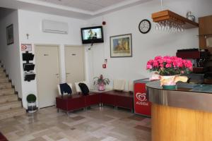 里米尼Hotel Amados的一间设有柜台和墙上电视的等候室