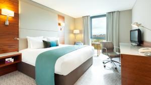 伦敦皇冠假日伦敦多克兰酒店的酒店客房配有一张床、一张书桌和一台电视。