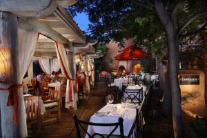 圣达菲洛雷托Spa旅馆的一间设有白色桌椅和树的餐厅