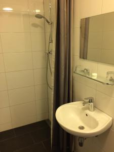 阿姆斯特丹贝灵顿酒店的浴室配有盥洗盆和带镜子的淋浴