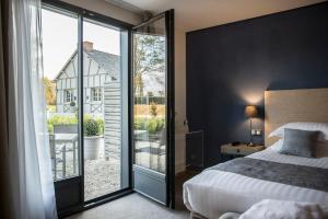 勒特隆歇Hôtel de l'Abbaye Le Tronchet Saint Malo的一间卧室设有一张床和一个滑动玻璃门