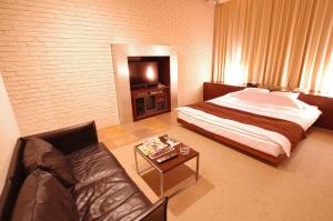 札幌八方蓝色情趣酒店（仅限成人入住）的一间卧室配有一张床、一张沙发和一张桌子