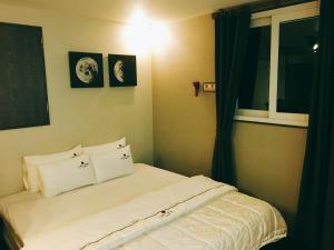 釜山IDEA酒店的卧室配有带枕头的床铺和窗户。