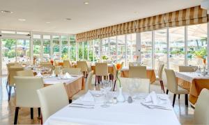 阿尔库迪亚港阿尔库迪亚港集团酒店的餐厅设有白色的桌椅和窗户。