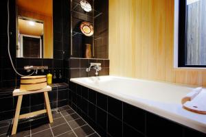 京都町屋红叶度假屋的浴室设有白色浴缸和黑色瓷砖。