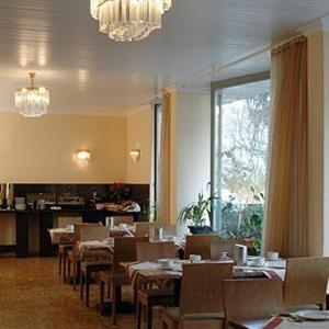 美因河畔法兰克福墨卡托城市酒店的一间带桌椅和吊灯的餐厅