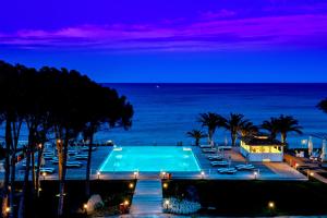 卡斯蒂亚达斯La Villa Del Re - Adults Only - Small Luxury Hotels of the World的一个带椅子的游泳池,晚上则享有海景