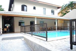 瓜鲁雅Parque Suites Com Ar Condicionado Piscina e Estacionamento的一座房子,旁边设有游泳池