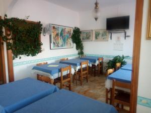 因佩里亚Pensione Aurora的餐厅设有蓝色的桌椅和电视。