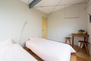 东京葡萄屋高圆寺旅舍的白色墙壁客房的两张床