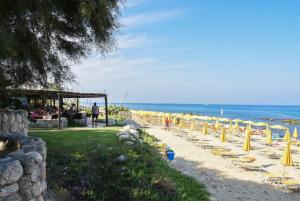 梵蒂冈角Baia Del Sole Resort的海滩上的一排椅子和遮阳伞