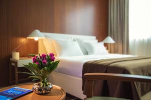 赖阿南纳千年公寓的一间酒店客房,配有一张桌子上花瓶的床