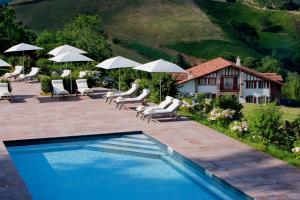 比达莱奥斯塔佩旅馆的一个带椅子和遮阳伞的游泳池以及一座房子