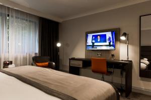 泰恩河畔纽卡斯尔纽卡斯尔乔治华盛顿高尔夫Spa美居酒店的酒店客房配有一张床和一张书桌及一台电视