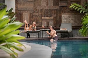 沙努尔阿卡纳精品酒店的坐在游泳池里的男人和女人