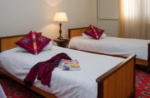努库斯吉皮克洁丽宾馆的两张床铺,位于酒店房间,配有浴袍