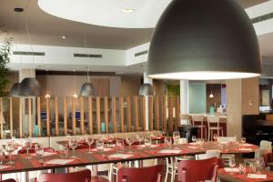 马拉加钟楼马拉加机场酒店的餐厅设有一张长桌子和红色椅子